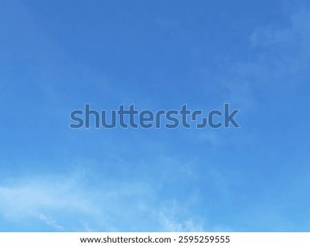 A serene blue sky with soft, wispy clouds scattered throughout. The natural gradient of the sky creates a calming and peaceful atmosphere, perfect for backgrounds, textures, or conceptual imagery