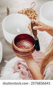 A serene close-up of a person holding a Tibetan singing bowl during a wellness retreat. The image captures the essence of sound healing and mindfulness practices, with the soothing ambiance of crystal