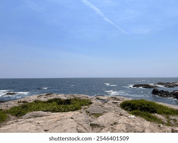  A serene coastal landscape featuring rocky shores, clear blue skies, and calm ocean waters, creating a peaceful and refreshing natural setting. - Powered by Shutterstock