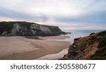 A serene coastal landscape featuring rugged cliffs and a sandy beach at sunset. The tranquil waters of the ocean gently meet the shoreline along the picturesque coastline of Portugal.