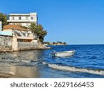 A serene coastal scene captured in Annaba, Algeria, showcasing a small white motorboat gently floating on the calm Mediterranean Sea.