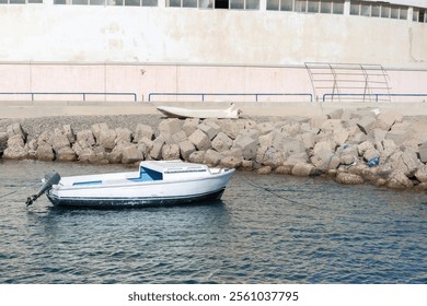 Serene coastal scene with white boat moored near rocky shoreline - Powered by Shutterstock