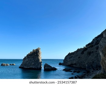 Serene coastal view featuring dramatic rock formations rising from the deep blue sea under a cloudless sky. A tranquil seascape perfect for nature lovers and travel enthusiasts. - Powered by Shutterstock