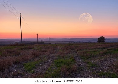 A serene countryside landscape at dusk, featuring a glowing moon rising over rolling hills and a lone tree. Power lines stretch across the sky, adding a touch of human presence to the natural beauty. - Powered by Shutterstock