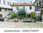 Serene courtyard within a historic St. Naum monastery, Ohrid, featuring traditional stone architecture, lush greenery, and wooden benches. North Macedonia.