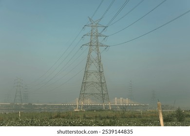 Serene dawn at Yamuna riverbanks with Delhi's under-construction bridge and power lines against the morning sky, capturing the blend of nature and urban growth along the river’s edge. Delhi, India - Powered by Shutterstock