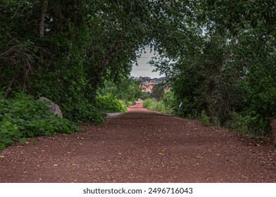 Serene dirt pathway through dense green forest leading to red rock formations. Ideal for concepts of tranquility, nature, and journeys. - Powered by Shutterstock