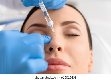 Serene female receiving collagen in nose