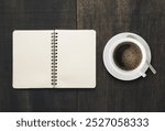 A serene flatlay featuring a blank notebook beside a cup of black coffee on a wooden table. Perfect for portraying creativity, comfort, and relaxation.