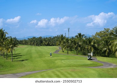 A serene golf course with lush greenery, palm trees, and a clear blue sky, featuring a golfer and a golf cart on the winding path. - Powered by Shutterstock