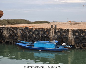 A serene harbor scene with blue boats docked alongside an aged, weathered pier. - Powered by Shutterstock