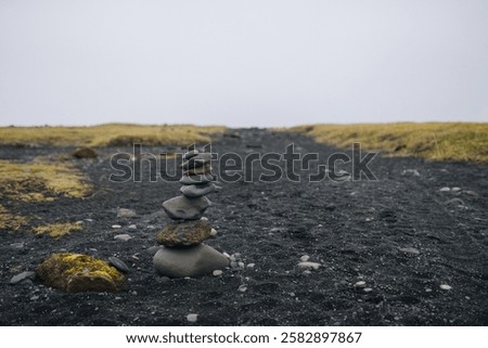 A serene image of a stone pyramid carefully balanced on a beach of black sand