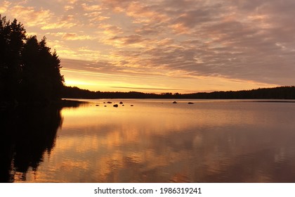 Serene lake reflecting cloudy sky and forest in a sunset of Finnish nature. - Powered by Shutterstock