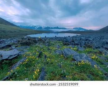 A serene lakeside scene with colorful wildflowers, rocky terrain, majestic mountains, and a vibrant tent under a dramatic sky. - Powered by Shutterstock