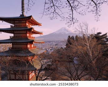 A serene landscape features a vibrant pagoda among bare trees, with a majestic snow-capped peak towering in the pastel sky. - Powered by Shutterstock