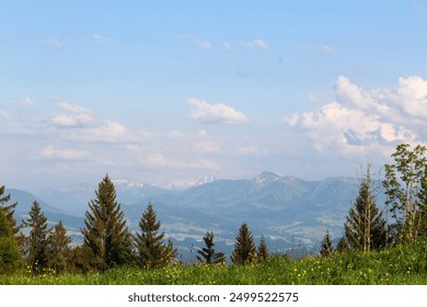 A serene landscape featuring rolling mountains in the background with snow caps, lush greenery, and a clear blue sky, creating a peaceful and picturesque nature scene. - Powered by Shutterstock