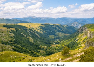 A serene landscape featuring a valley encircled by sunlit mountains - Powered by Shutterstock