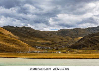 Serene landscape with rolling hills, tiny scattered homes, dramatic clouds, and a still lake reflecting the natural beauty and muted earth tones. - Powered by Shutterstock