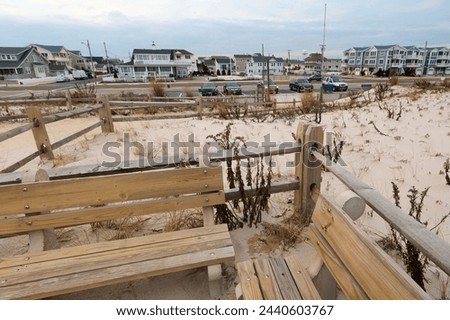 A serene landscape showing coastal houses lined behind sandy dunes, fenced by a wooden fence, capturing the tranquil essence of coastal living.