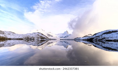 The serene landscape, with snow-capped mountains, a calm lake, and a cloudy sky, evokes a sense of tranquility and winter's chill. - Powered by Shutterstock