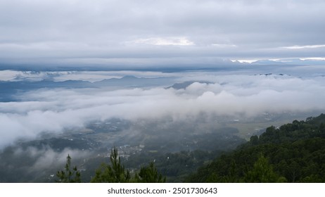 serene landscape view with dense clouds covering valleys, distant mountains, and lush green forests below. - Powered by Shutterstock