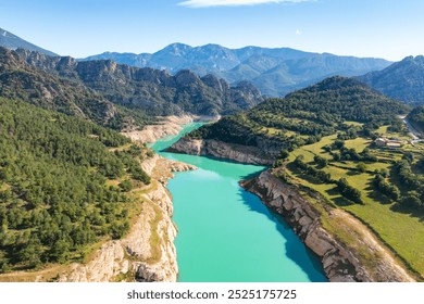 Serene Llosa del Cavall Reservoir on Cardener River nestled in Catalonian mountains, featuring turquoise waters, lush greenery, and rugged cliffs under clear summer sky - Powered by Shutterstock