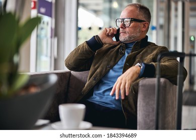 Serene Male Tourist In Eyeglasses Calling On His Smartphone In The First Class Airport Lounge