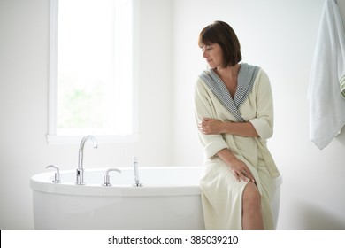 Serene mature woman sitting by a bathtub