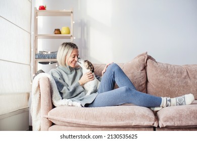 Serene Middle-aged Lady Housewife Lounge Sit On Sofa And Play With Dog, Calm 40s Adult Woman Rest On Comfort Couch, Puppy Kissing Female