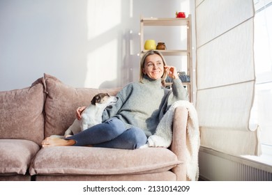 Serene Middle-aged Lady Housewife Lounge With Dog Sit On Sofa, Calm 40s Adult Woman Rest On Comfort Couch Breath Fresh Air In Cozy Living Room At Home