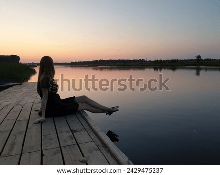 Serene moments: a man sitting alone on a wooden dock enjoying a serene sunset over a calm lake