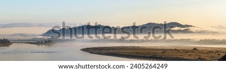 The serene morning haze settles over the Irrawaddy River, framing the Bala Min Htin Bridge in Myitkyina, Myanmar, a blend of nature's tranquility and human ingenuity
