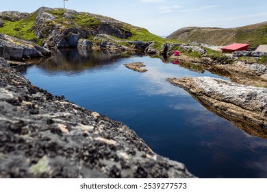 Serene mountain landscape featuring a reflective lake surrounded by rocky hills, under a clear blue sky. Perfect for nature lovers and outdoor enthusiasts seeking tranquility and inspiration. - Powered by Shutterstock