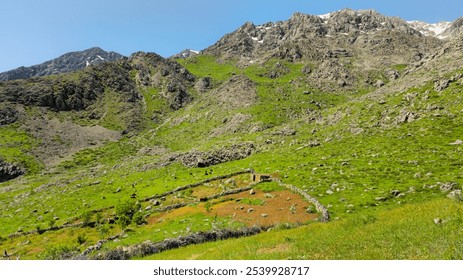 A serene mountain landscape with lush green fields, rocky terrain, and a small stone structure under a clear blue sky.
📍 Hawraman Takht, Kurdistan - Iran  - Powered by Shutterstock