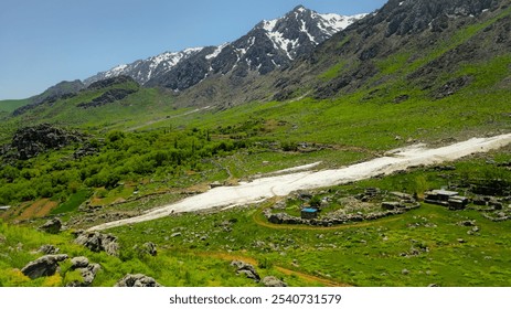 A serene mountain landscape with lush green fields, scattered trees, and snow-capped peaks under a clear blue sky.
📍 Hawraman Takht, Kurdistan - Iran  - Powered by Shutterstock