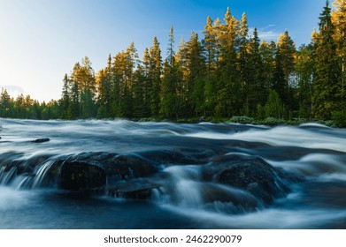 A serene mountain river rushes through a lush, forested area in Norway. The setting sun casts a golden glow on the trees. - Powered by Shutterstock