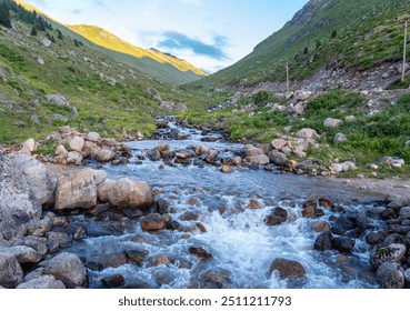 A serene mountain stream flowing through the rocky terrain of Amaklit Plateau in Camlihemsin, Turkey, surrounded by lush greenery and a clear blue sky, capturing the untouched beauty of nature - Powered by Shutterstock