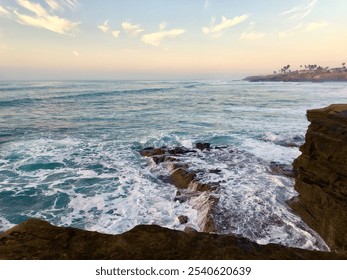 A serene ocean view captured at the san diego coastline during sunset, featuring gentle waves crashing against a rugged rocky shoreline. - Powered by Shutterstock