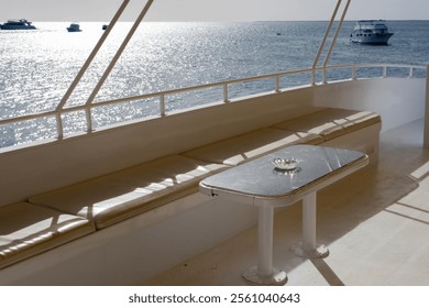 Serene ocean view from yacht deck with benches and table at sunset - Powered by Shutterstock