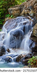 Serene pond with a waterfall over rocks. Landscape of a small natural spring near a clear pool on a mountain trail. Relaxing peaceful nature scene. Calm background of water flowing on stone outside - Shutterstock ID 2175131071