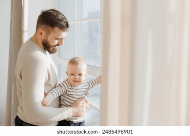 Serene portrait of father baby interaction by window, with dad attentive gaze and little son curious exploration emphasizing familial connection. - Powered by Shutterstock