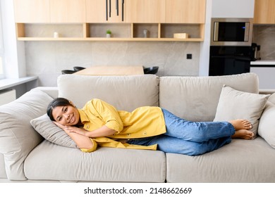 Serene Relaxed Young African-American Woman Looking At Camera Lying Down On The Sofa, Calm And Smiling Resting At Home, Enjoying Lazy Weekend At Home