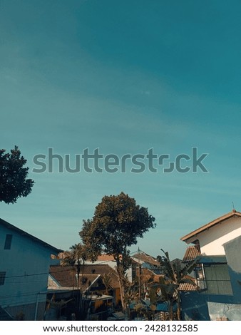 serene residential area under a clear blue sky. Houses with different architectural designs and trees are visible, portraying a peaceful and calm environment.