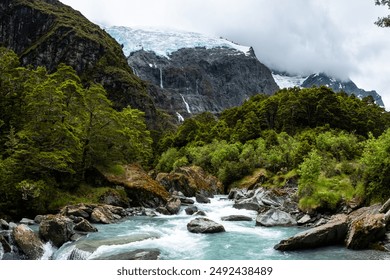 A serene river flowing through a mountain valley, with a majestic waterfall and lush forest creating a picturesque landscape. - Powered by Shutterstock