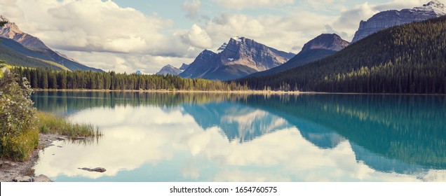 Serene Scene By The Mountain Lake In Canada With Reflection Of The Rocks In The Calm Water.