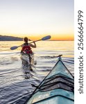 A serene scene of a person kayaking at sunset with scenic views of Vancouver