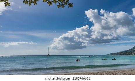 Serene seascape. Boats and yachts in the turquoise ocean. Green foliage against the sky and clouds. A wave rolls onto a sandy beach. Seychelles. Mahe. Beau Vallon - Shutterstock ID 2193766651