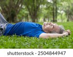 serene senior man lying down on grassess and taking a nap while resting in park,elderly lifestyle,exercise,relaxing and resting in nature