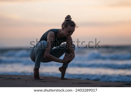 A serene silhouette of a woman gracefully flowing through yoga poses on the seashore as the sun paints the sky with hues of pink and gold.