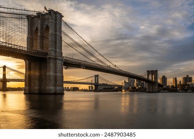 Serene sunset over Brooklyn Bridge, NYC skyline, calm waters, warm light, Manhattan Bridge, historic architecture - Powered by Shutterstock